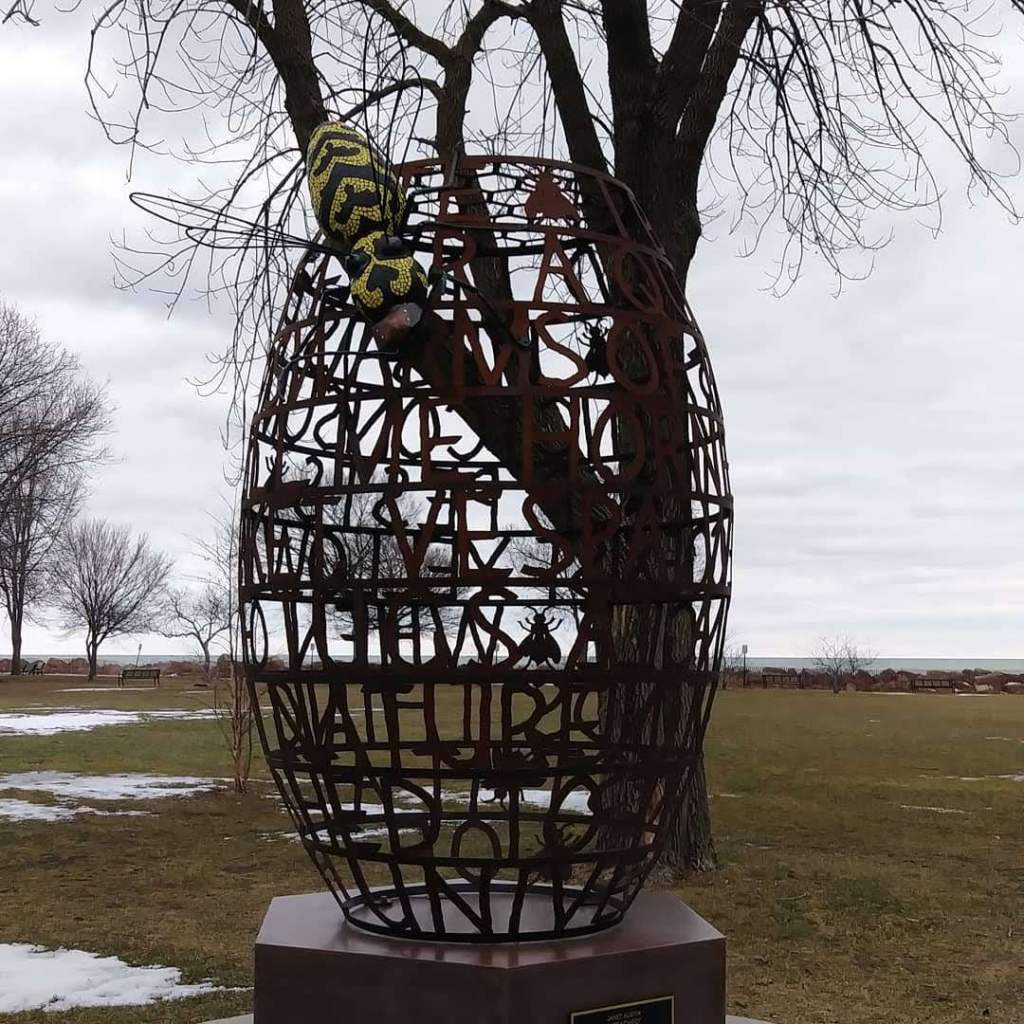 Objet de Arte in the park on the lake shore. Egg shaped sculpture with bee and the word nature hidden on the egg.
