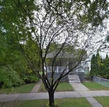 Frame house on a tree filled lot on a city street circa 1930