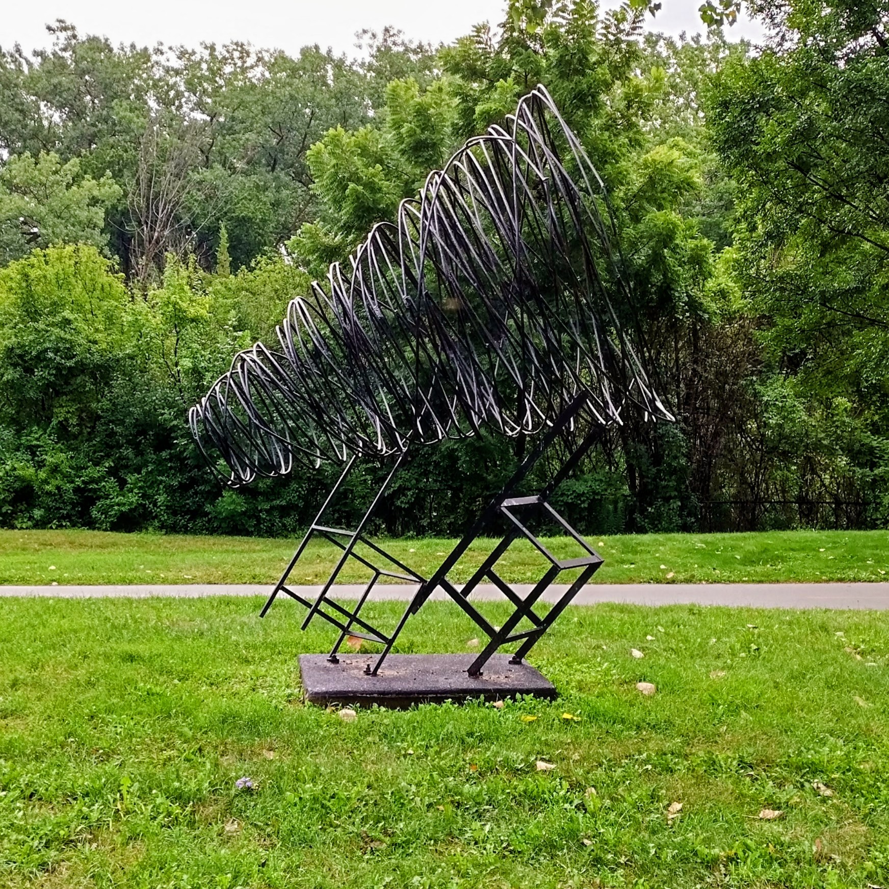 Objet d'art in Skokie Northshore Sculpture Park of a large conical spring precariously balanced a pair of cattywampus chairs
 
https://sculpturepark.org