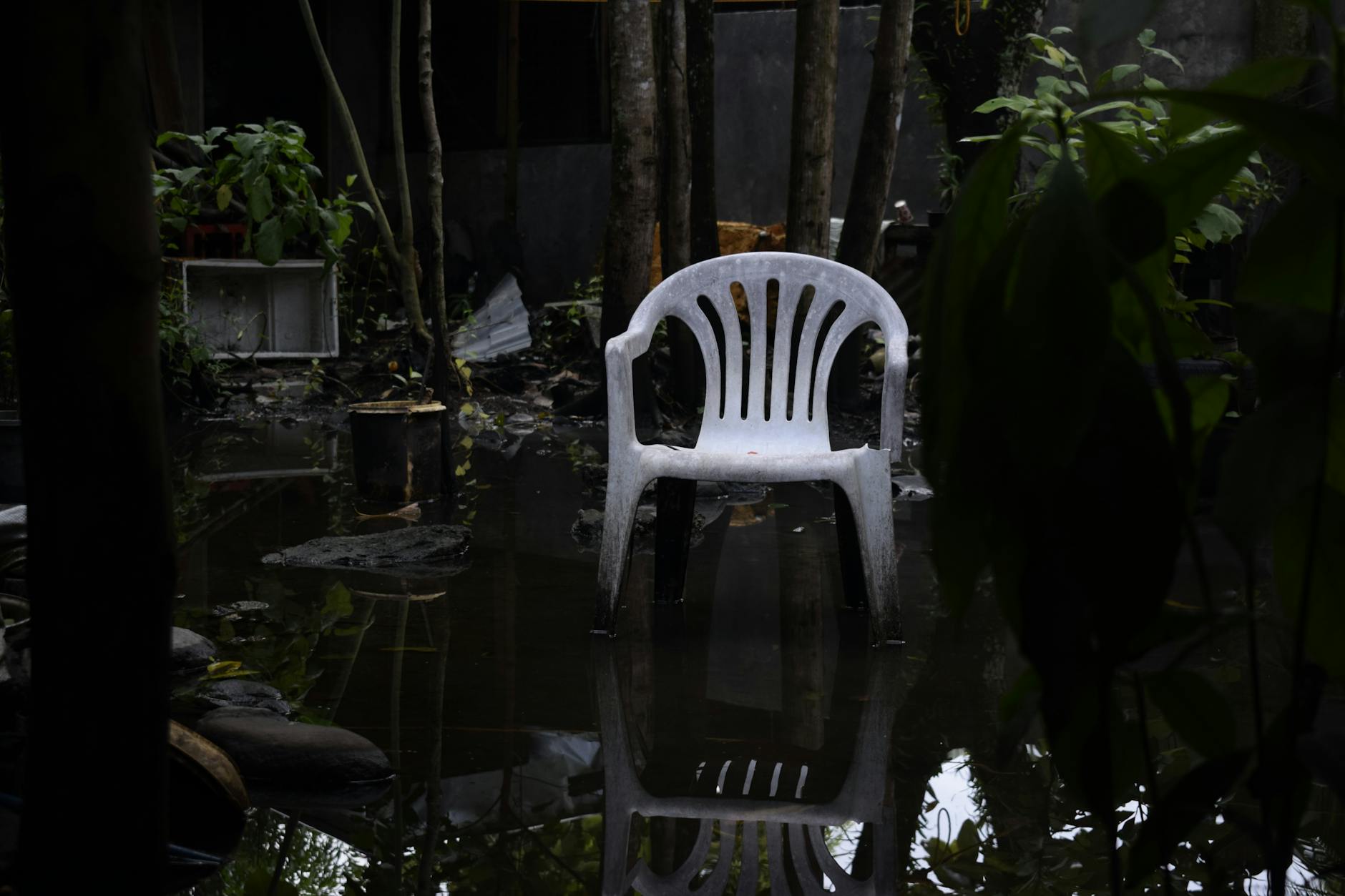 Stock photo of single plastic chair in a flooded wilderness of ruined household items from Pexel.com