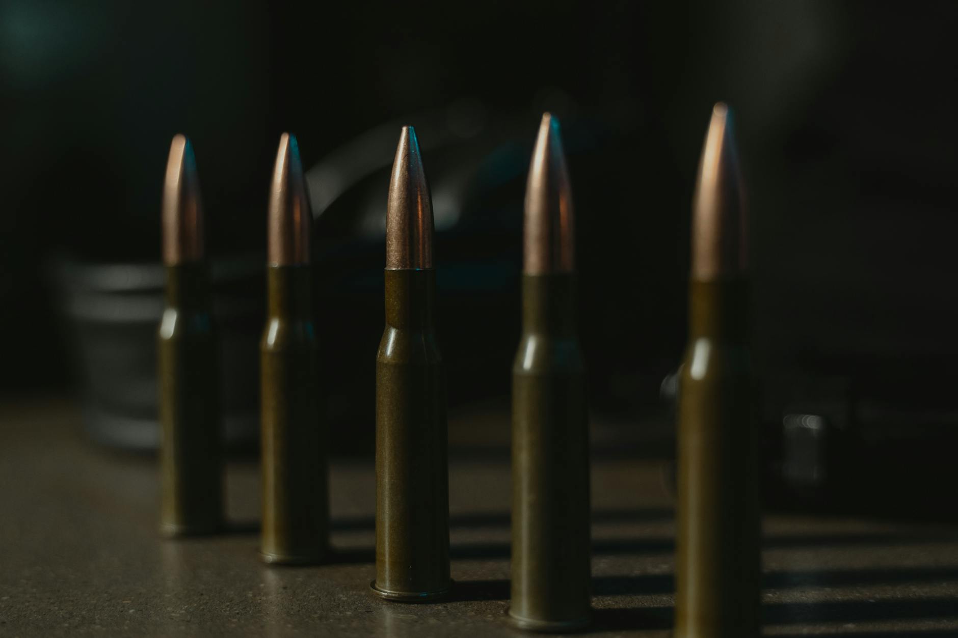 Stock photo of 5 large caliber bullets standing up in a row from Pexels.com