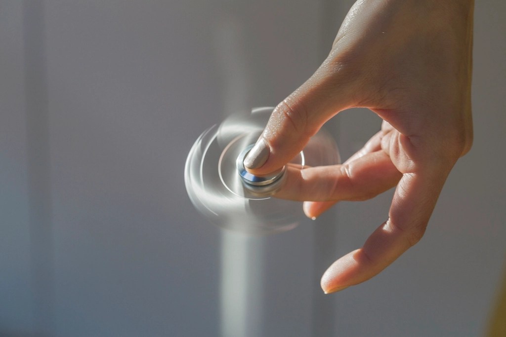 Stock photo of a spinning fidget widget spinning between a humans thumb and forefinger from Pexels.com 