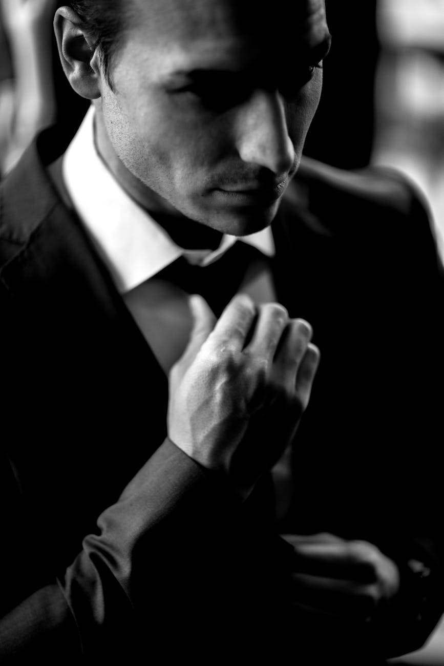 Stock B & W photo of a man in a suit adjusting his tie from Pexels.com 