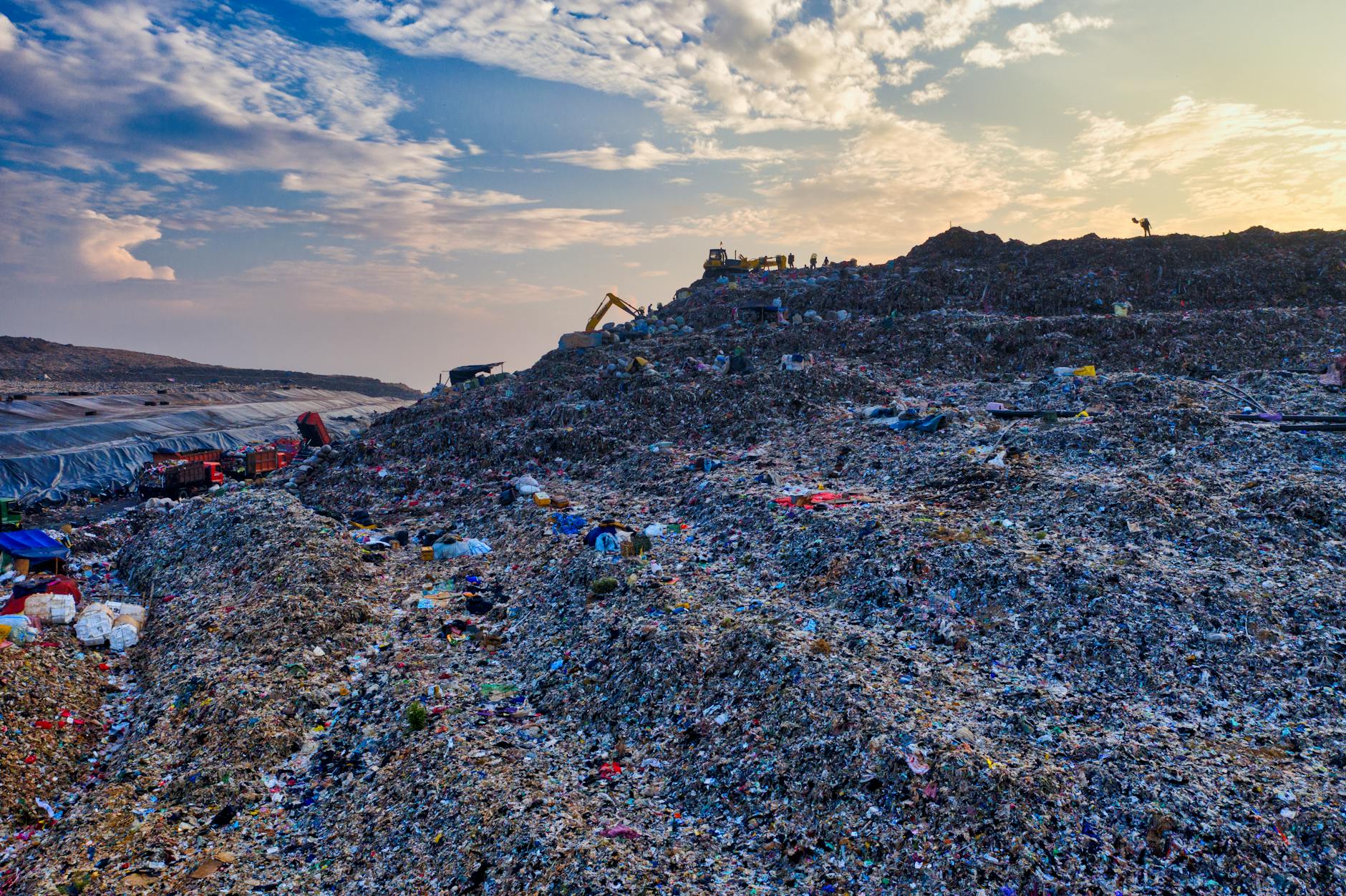 Stock photo of an expansive garbage dump with machinery in the background for trash moving from Pexels.com