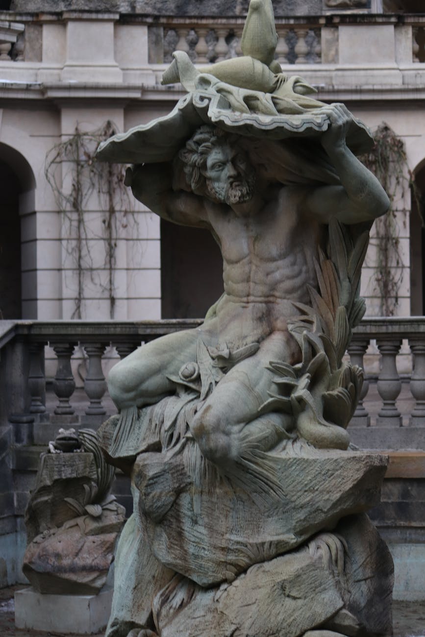 Stock photo of a statue of a bearded man huddled while seated on  a slab taking cover from the elements Pexel.com