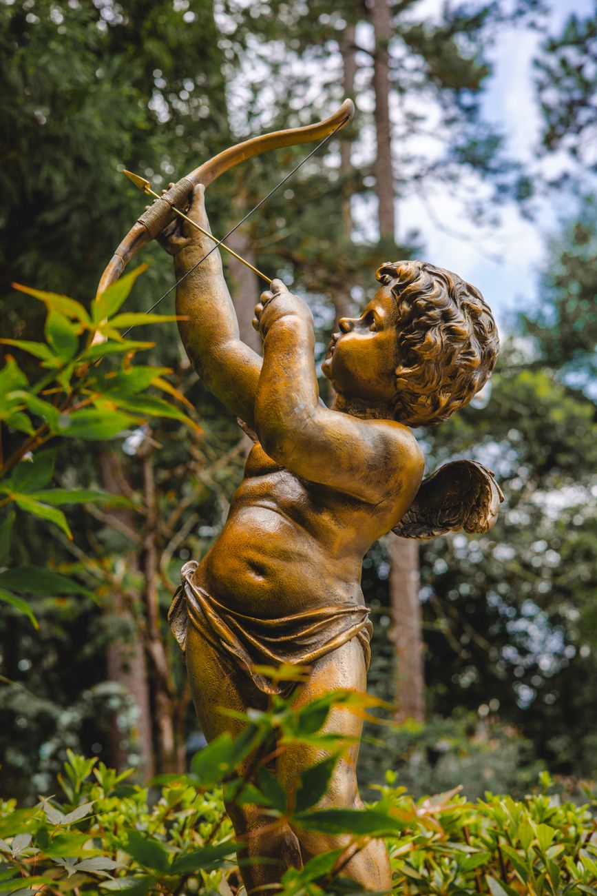 Stock photo of a statue of Cupid in a garden setting from Pexels.com 