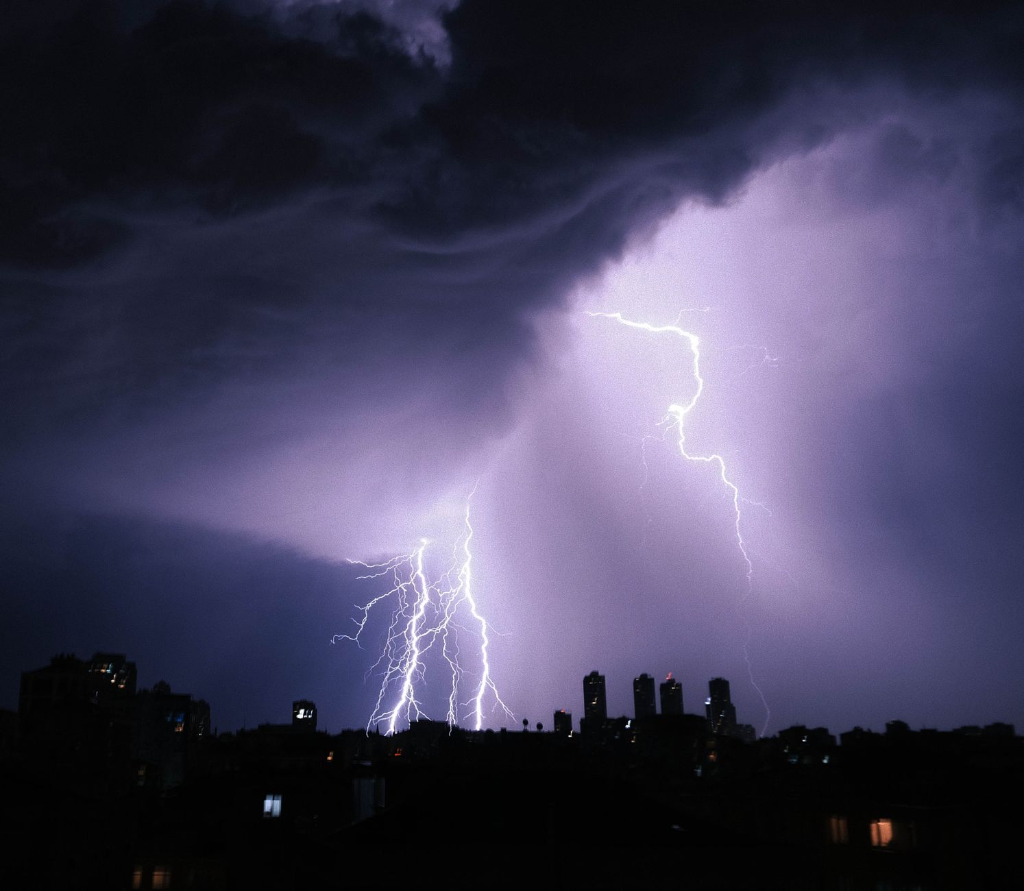 Stock photo of lightning and clouds with implied thunder following over a cityscape from Pexels.com 