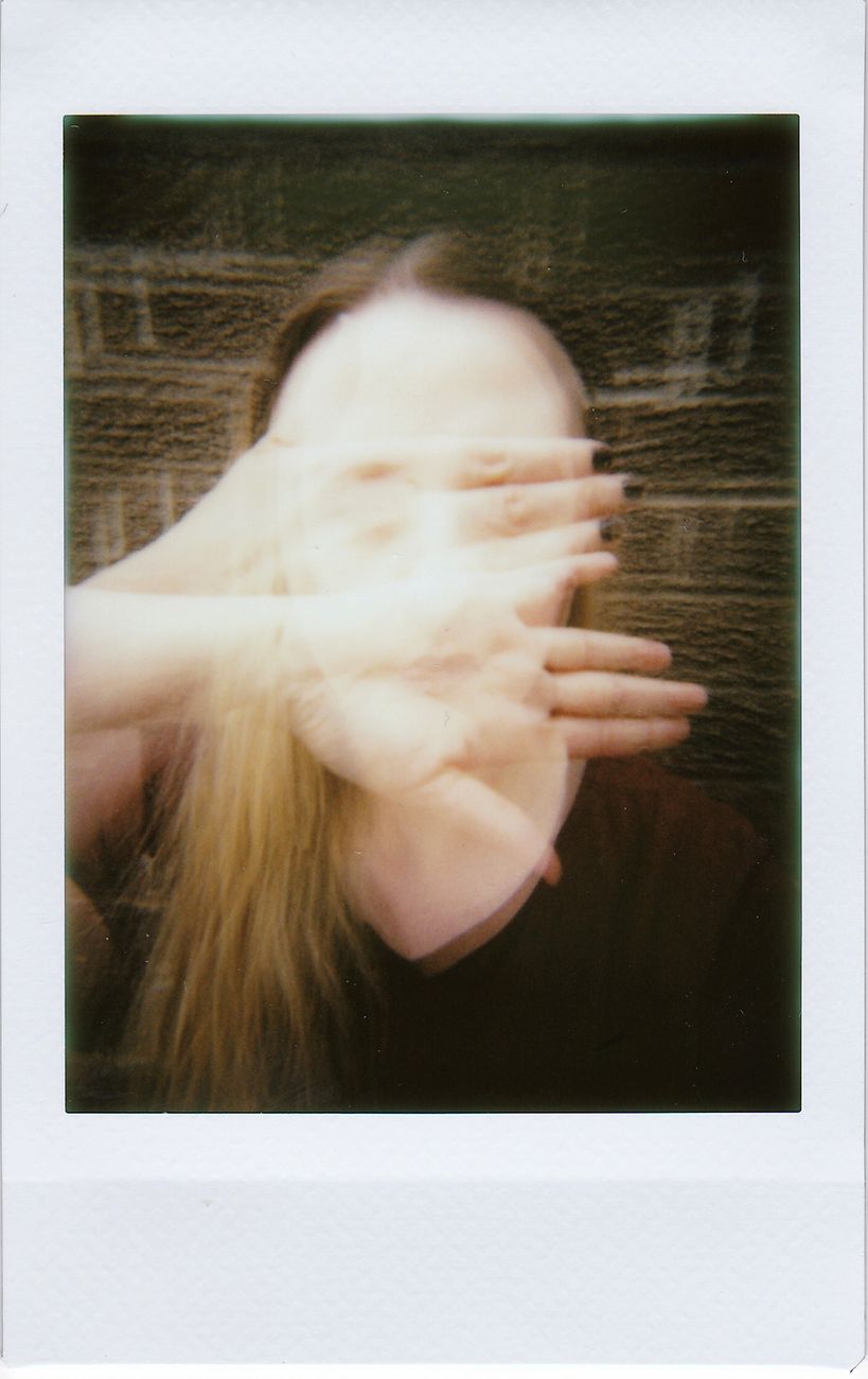 Stock photo of a blurry, candid Polaroid photograph of a person with long hair partially covering their face with their hands.from Pexels.com 