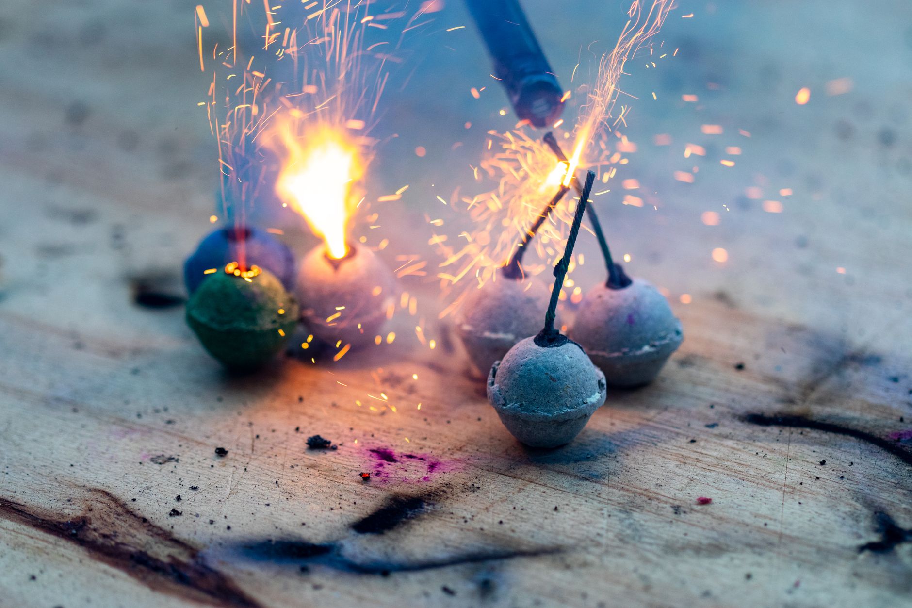 Stock image shows small spherical pyrotechnic bombs, igniting on a weathered wooden surface. from Pexels.com